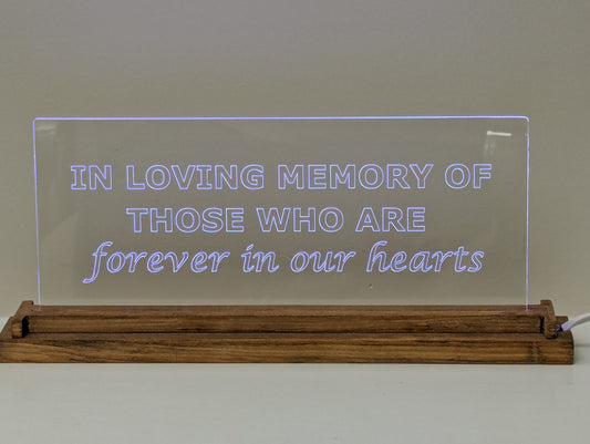 The heartfelt inscription 'In loving memory of those forever in our hearts' is beautifully displayed on clear, scratch-resistant acrylic, set in a stylish wood base with a white background.