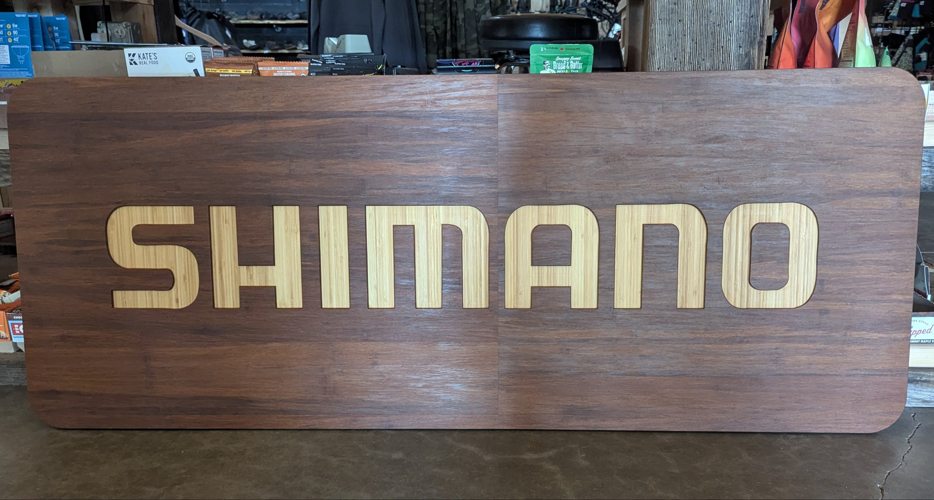 Wooden sign with 'Shimano' branding in a store setting
